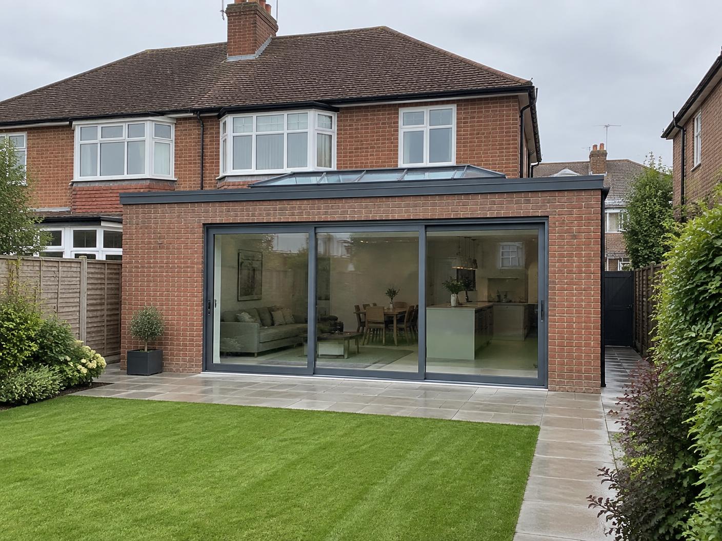 Completed single-storey rear extension with grey sliding doors and a roof lantern on a 1930s semi-detached house